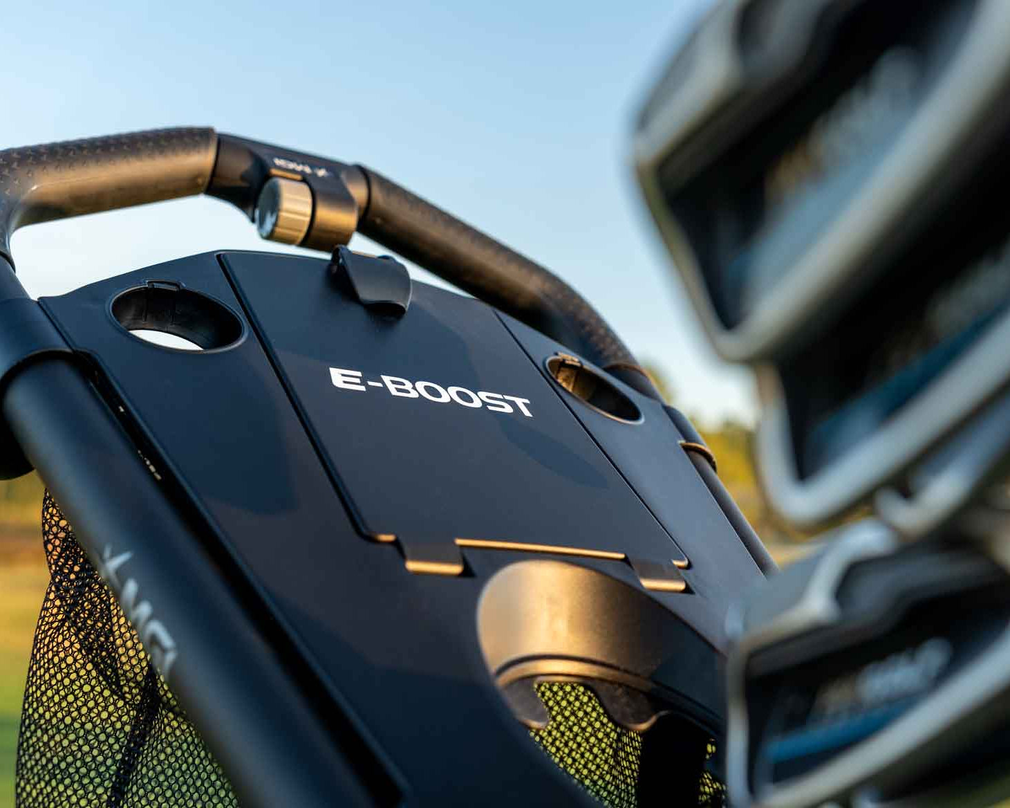 Close-up of a vehicle's handlebar with 'E-Boost' branding against a blurred outdoor background.