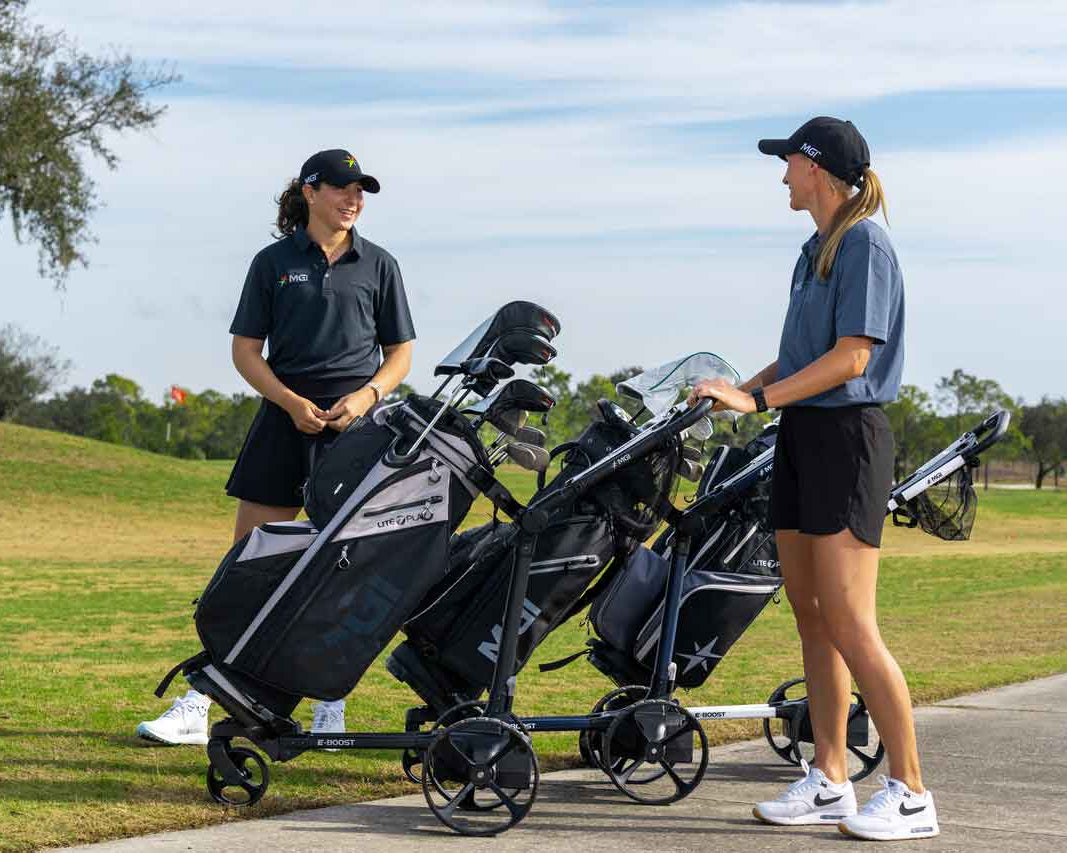 Two women with golf bags on a cart on a golf course